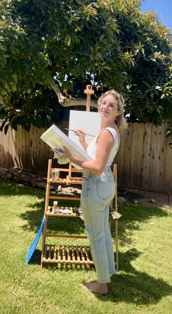 Elyse Hartnett painting at an easel in her garden
